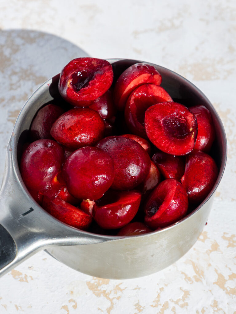 image of pitted and halved cherries in a measuring cup