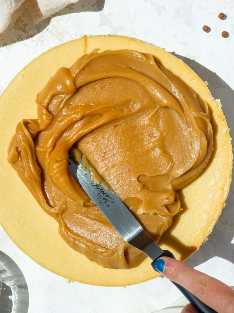 image of thick caramel being spread on top of a caramel cheesecake