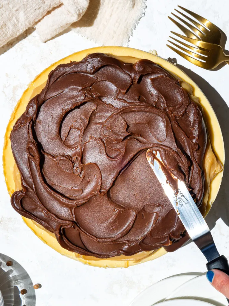 image of room temperature ganache being spread on top of a millionaire cheesecake