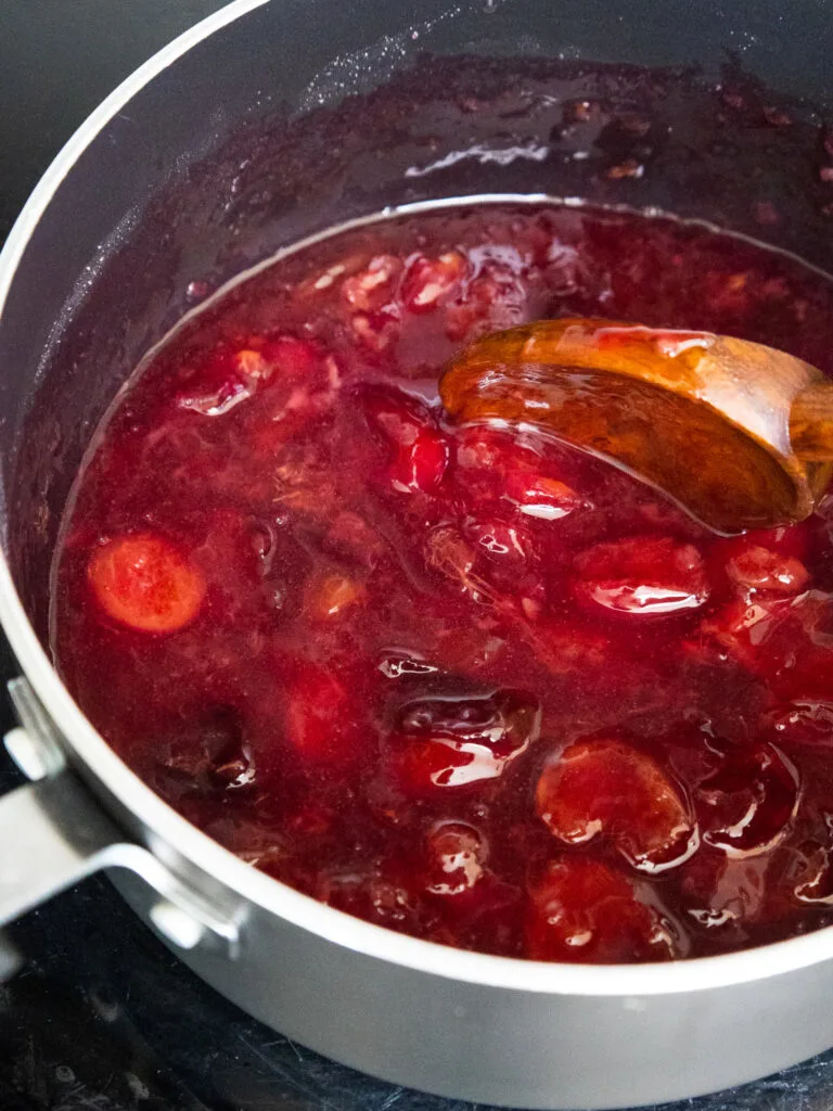 image of cherry topping being cooked down in a sauce pan until it thickens