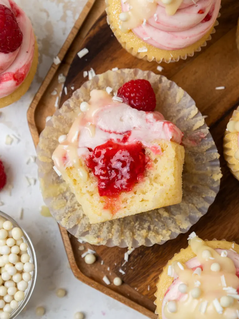 image of white chocolate raspberry cupcakes that have been cut into to show the raspberry jam filling