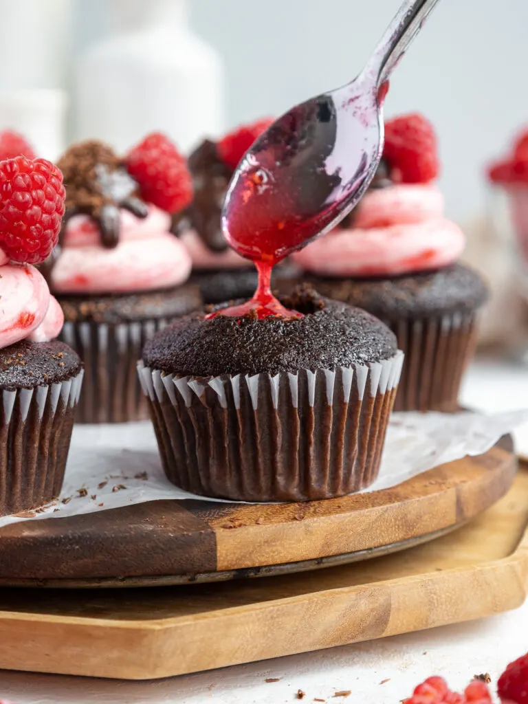 image of chocolate cupcakes being filled no raspberry jam