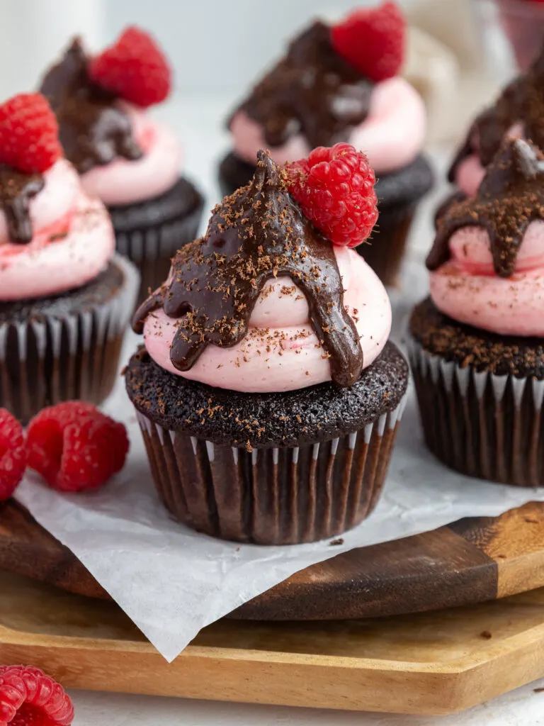 image of a chocolate raspberry cupcake that's been frosted with raspberry buttercream and topped with chocolate ganache