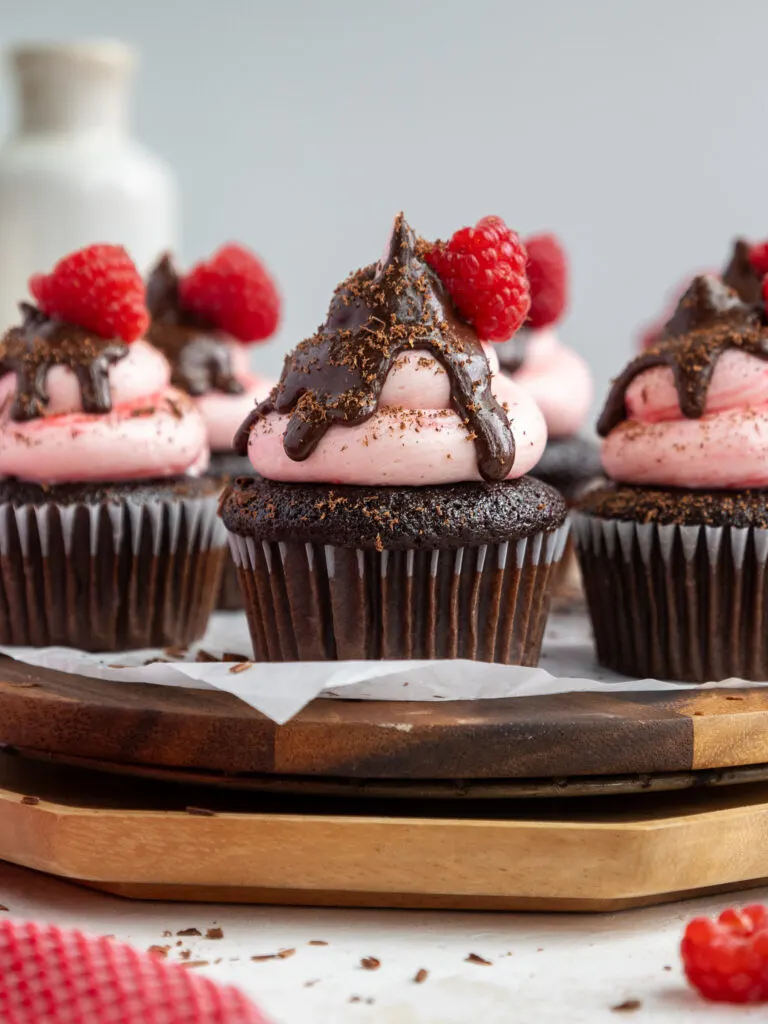 image of a chocolate raspberry cupcake that's been frosted with raspberry buttercream and topped with chocolate ganache