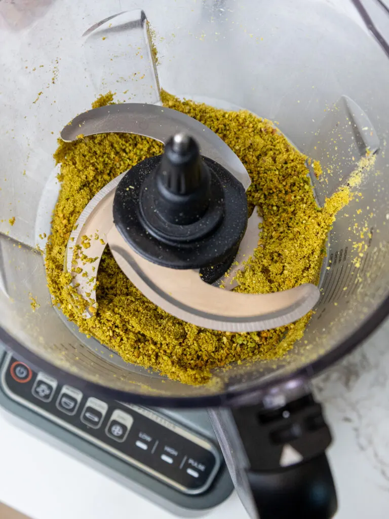 image of pistachios being ground finely in a food processor to make pistachio flour