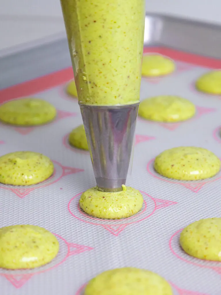 image of pistachio macaron shells being piped onto a Silpat mat