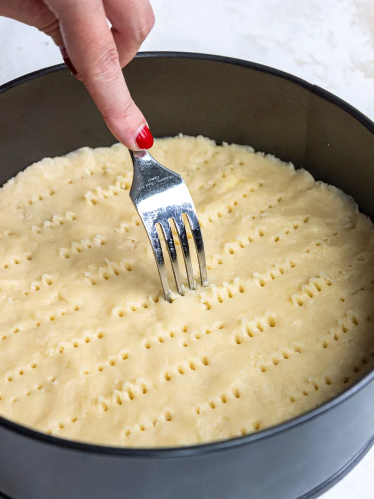 image of a shortbread crust being pricked with a fork to prevent it from puffing up as it bakes