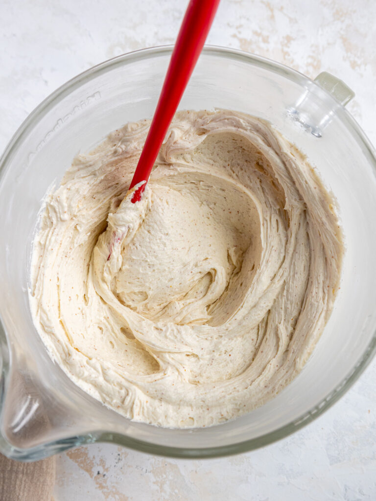image of brown butter cream cheese frosting that's been made in a large glass mixing bowl