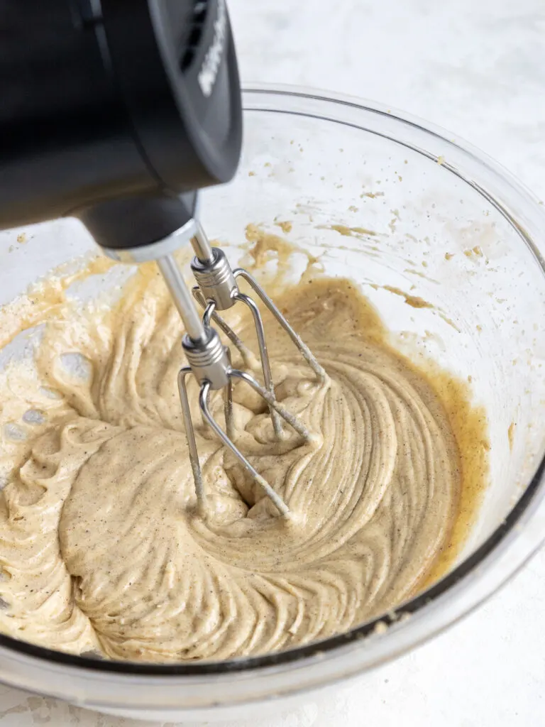 image of an egg being mixed into creamed butter and sugar with a hand mixer
