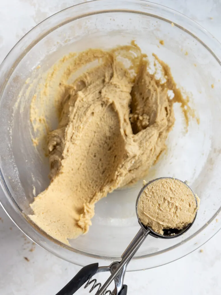 image of brown butter sugar cookie dough being scooped with cookie scoop