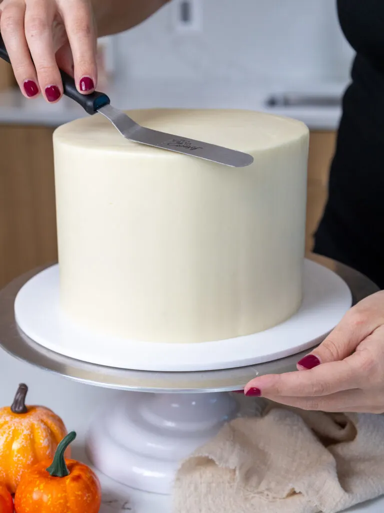 image of frosting being smoothed onto a cake with a small offset spatula