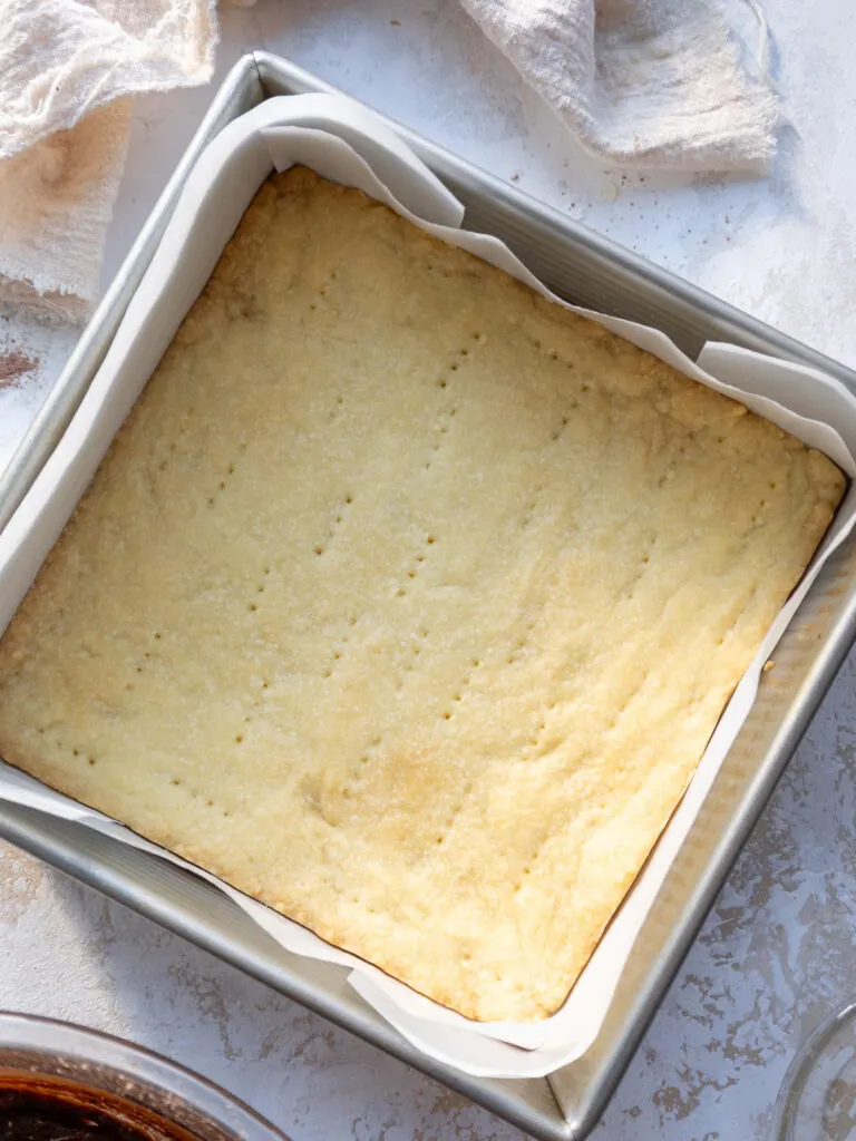 image of a baked shortbread crust in a square baking pan