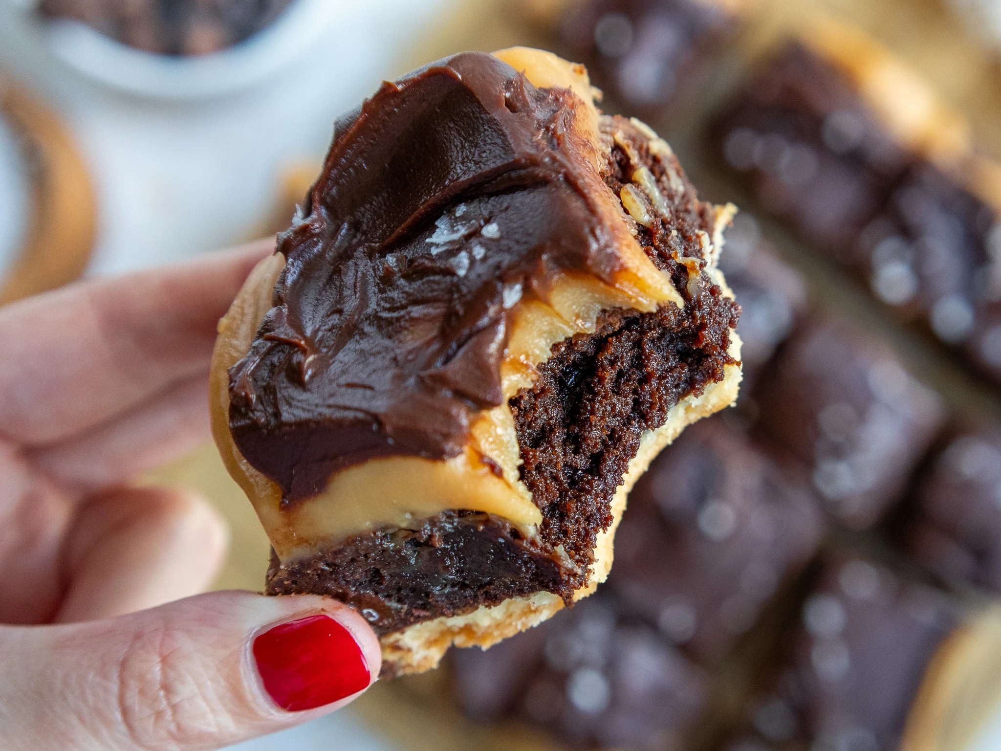 image of a millionaire brownie being held up to show it's caramel and ganache topping