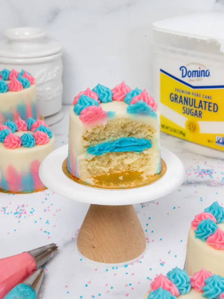 image of a mini gender reveal cake that's been cut into to show the blue frosting that it's filled with