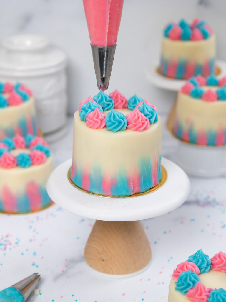 image of frosting swirls being piped on top of a mini gender reveal cake