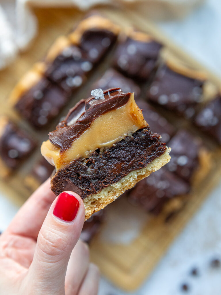 image of a millionaire brownie being held up to show it's caramel and ganache topping