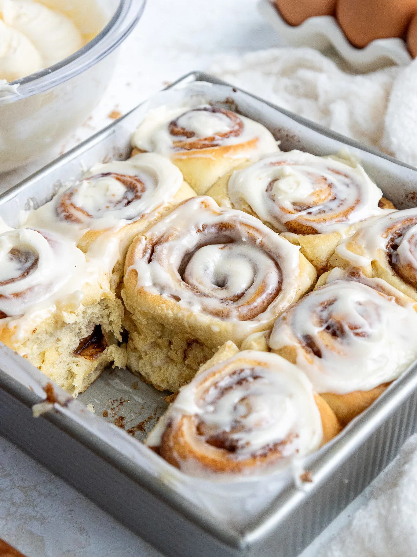 image of cream cheese frosting being added to cinnamon rolls