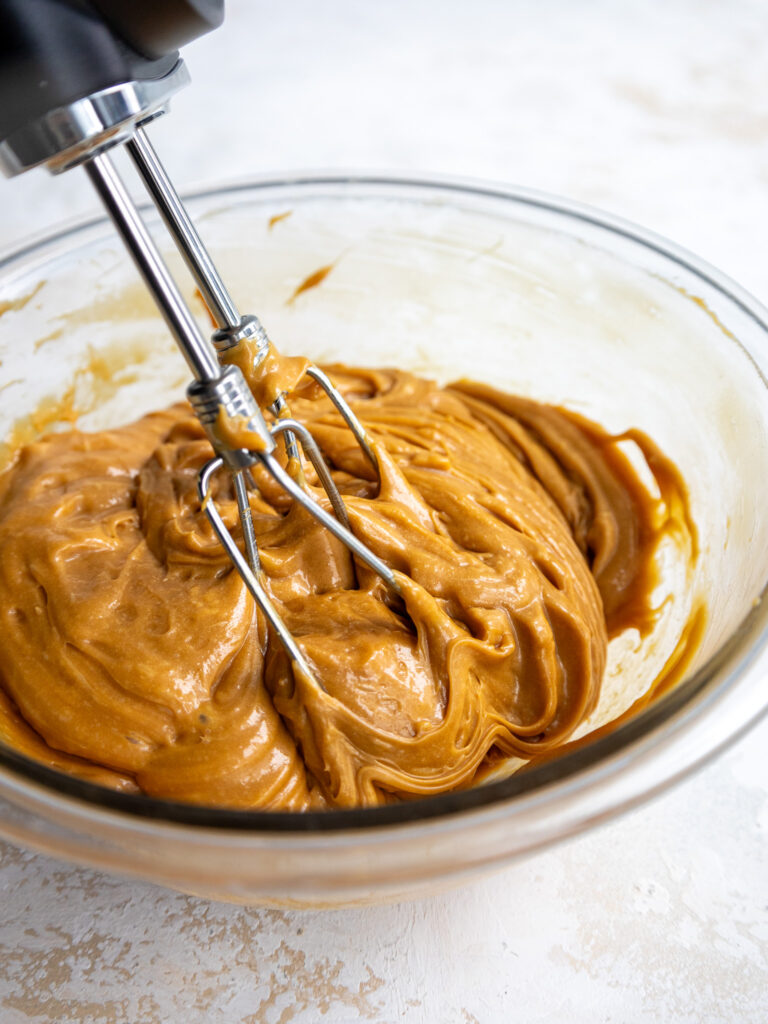 image of caramel being whipped up with a hand mixer in a glass bowl