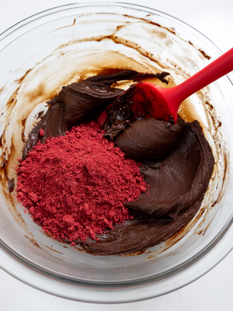 image of freeze dried raspberry powder being added to chocolate ganache