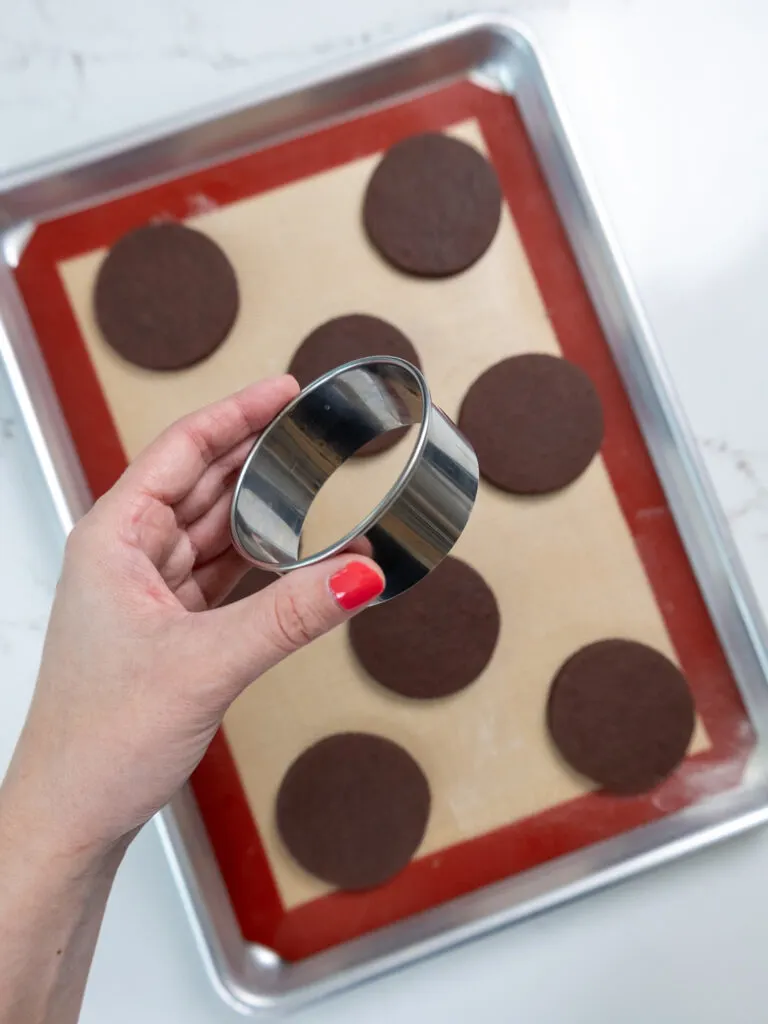 image of a 3-inch circle cookie cutter being held above a tray of cookies that were cut out using it