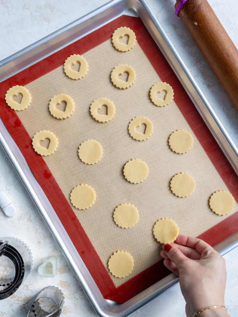image of linzer cookies that have been cut out and placed a lined baking tray before being baked