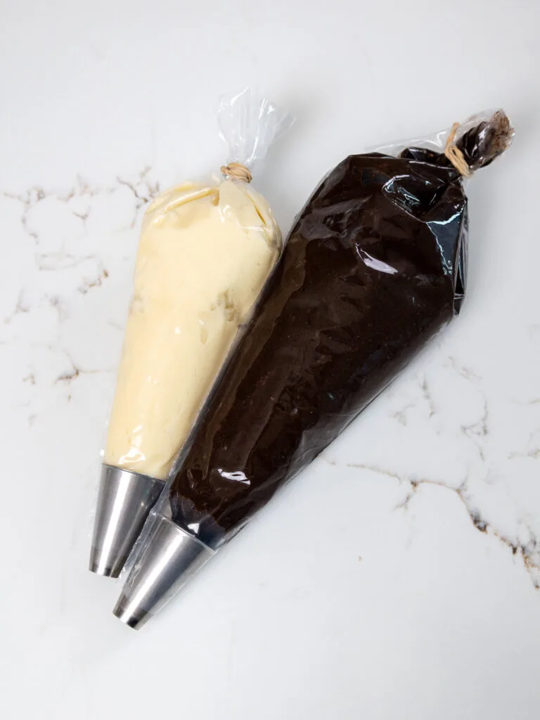 image of vanilla and chocolate buttercream in piping bags fitted with a large round piping tip