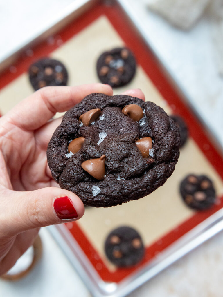 image of a double chocolate cookie being held up to show how chewy and soft it is
