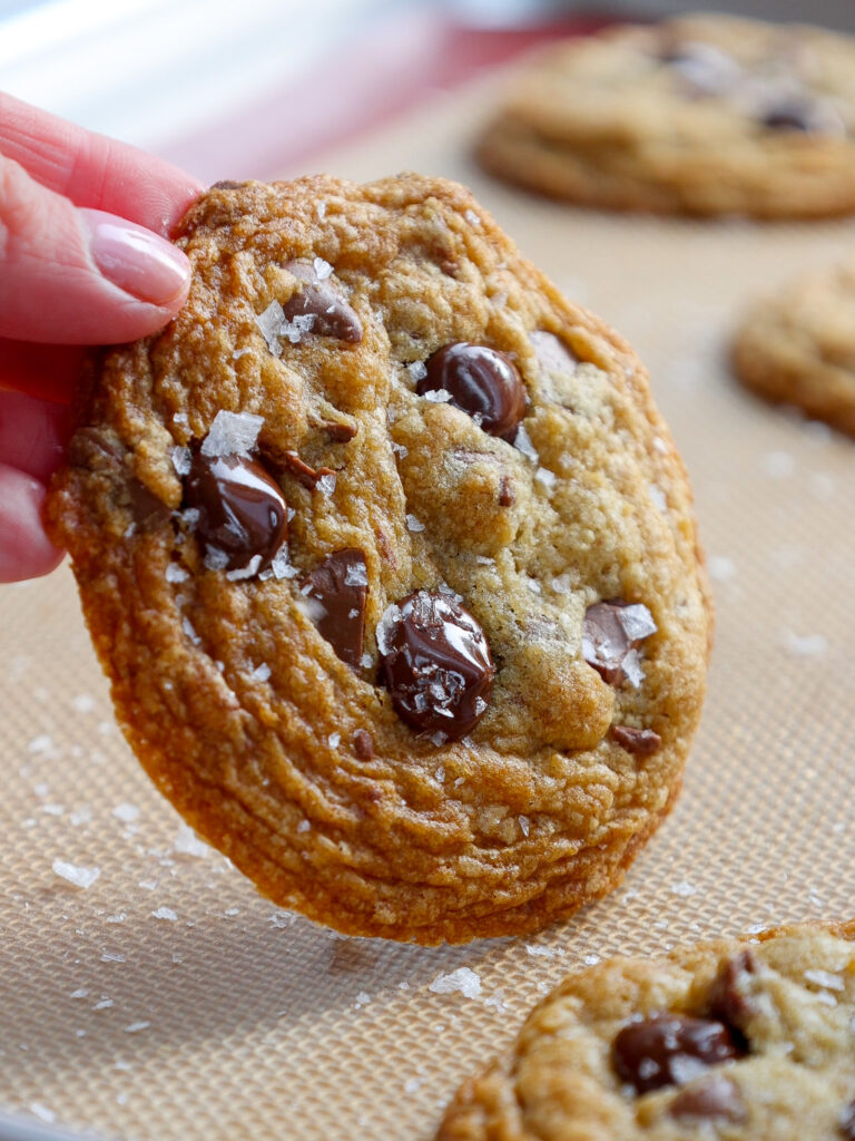 image of a no chill chocolate chip cookie being held up to show its perfectly crinkled edges and soft center