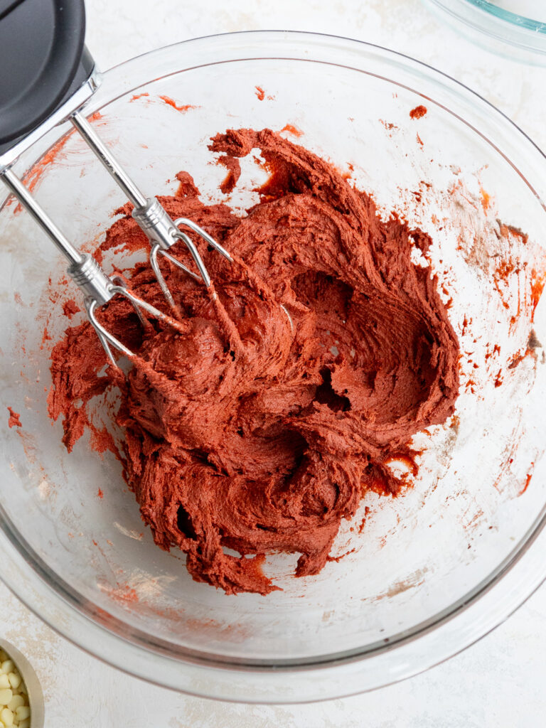 image of red velvet cookie dough being mixed with a hand mixer
