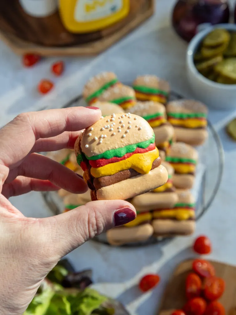 image of a burger macaron being held up
