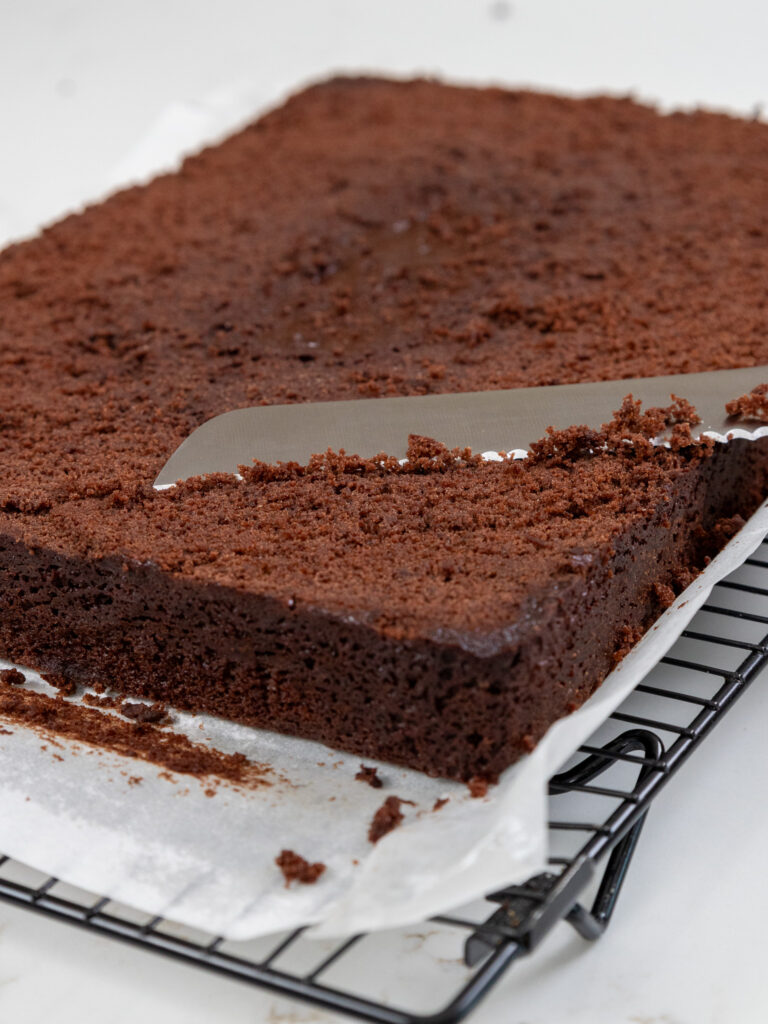 image of chocolate sheet cake being leveled with a serrated knife