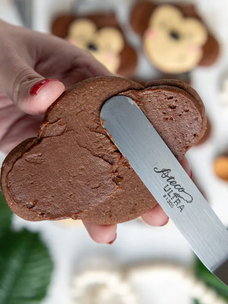 image of frosting being smoothed onto a monkey shaped cookie