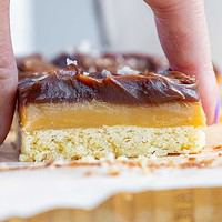 image of a millionaire bar that's been cut into a square to show it's thick layers of shortbread, caramel, and chocolate ganache