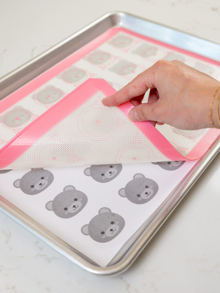 image of a bear macaron template being placed under a silicone mat