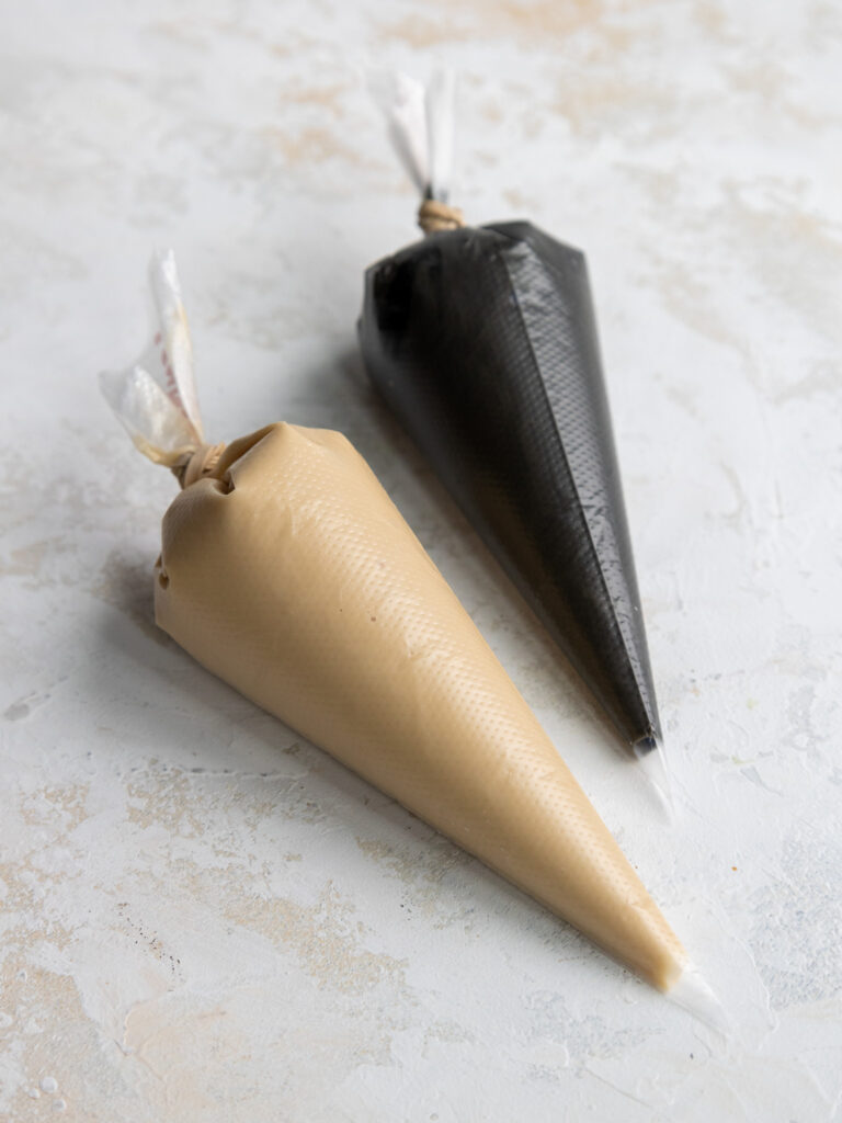 image of black and tan royal icing in small piping bags