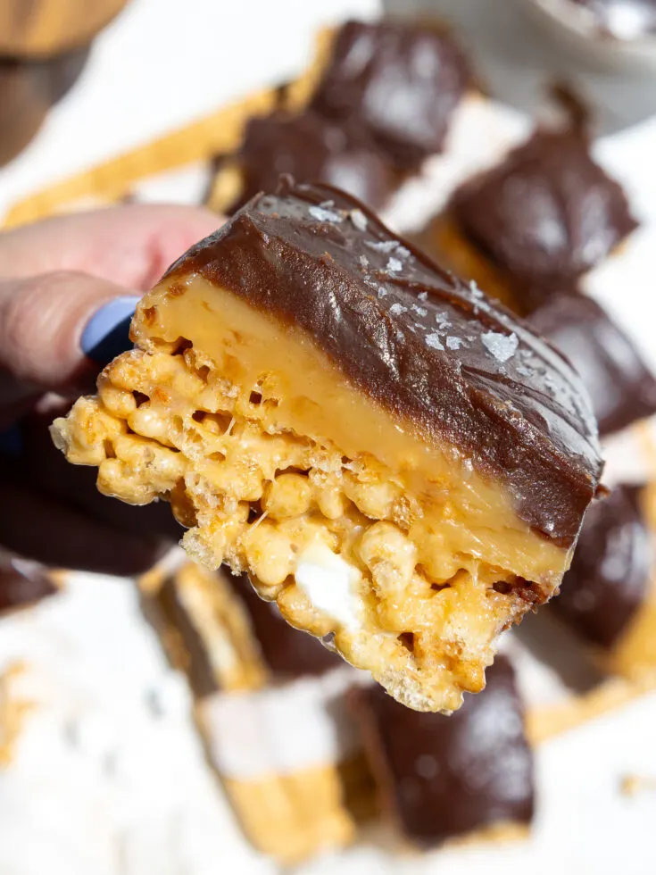 image of caramel chocolate rice krispies that have been cut to show their layers of caramel and chocolate ganache