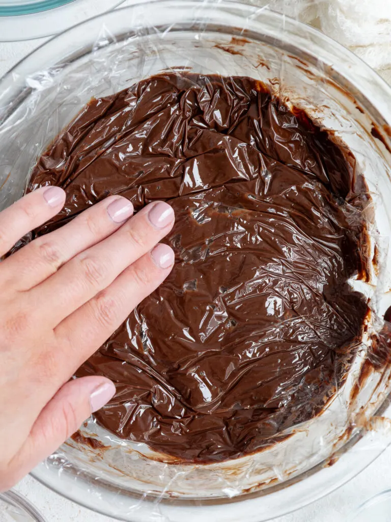 image of dark chocolate ganache being covered with plastic wrap before being set aside to cool