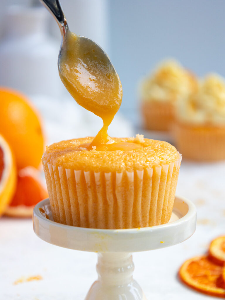 image of an orange cupcake being filled with orange curd