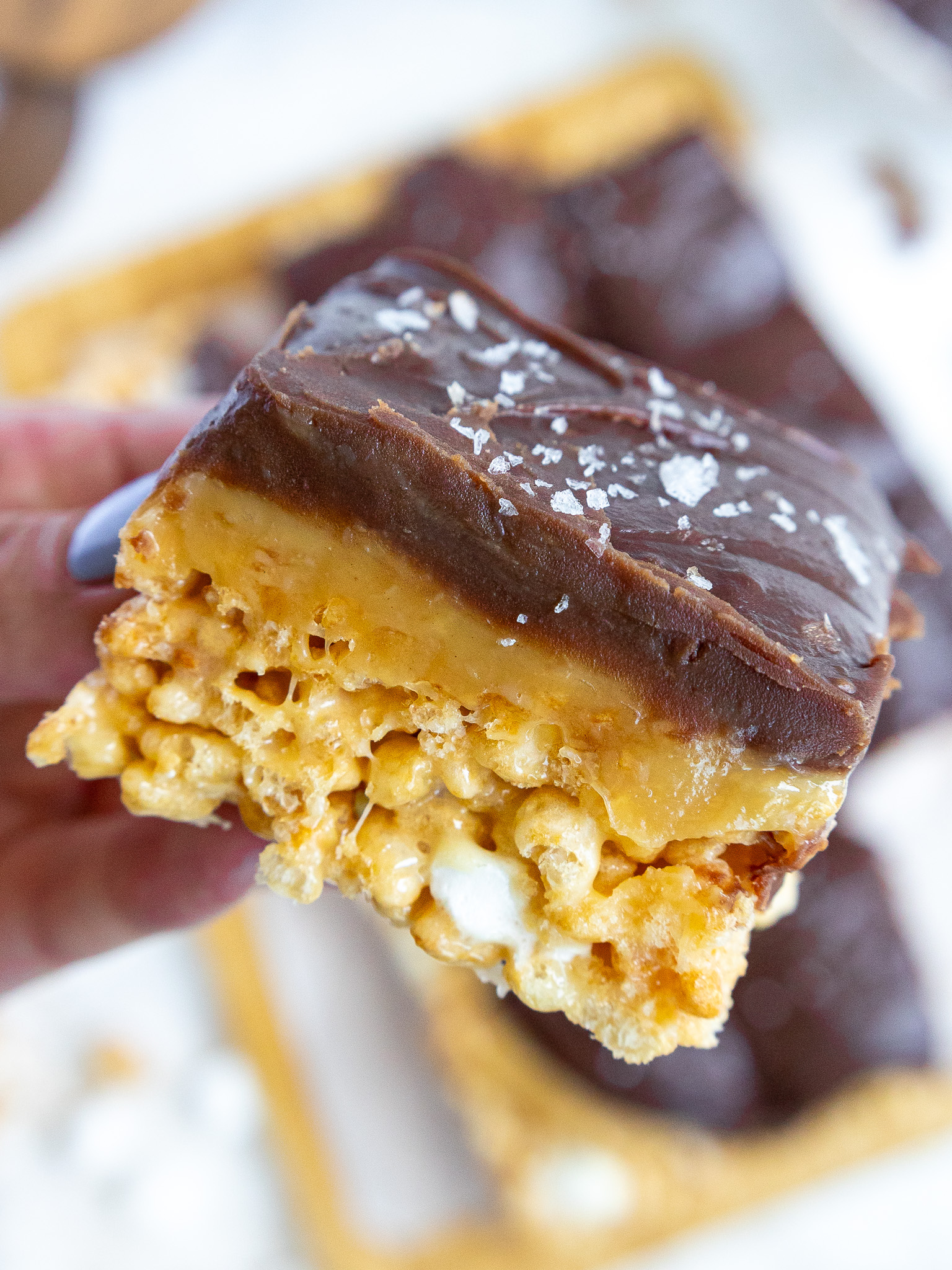 image of caramel chocolate rice krispies that have been cut to show their layers of caramel and chocolate ganache