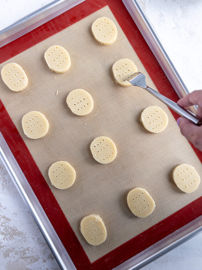 image of shortbread cookie dough being poked with a fork to prevent them from puffing up