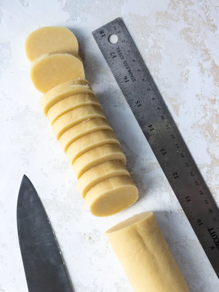 image of shortbread cookie dough that's been cut into half inch thick rounds with a sharp knife