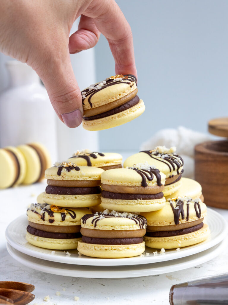image of a millionaire macaron being held up to show its caramel and chocolate ganache filling