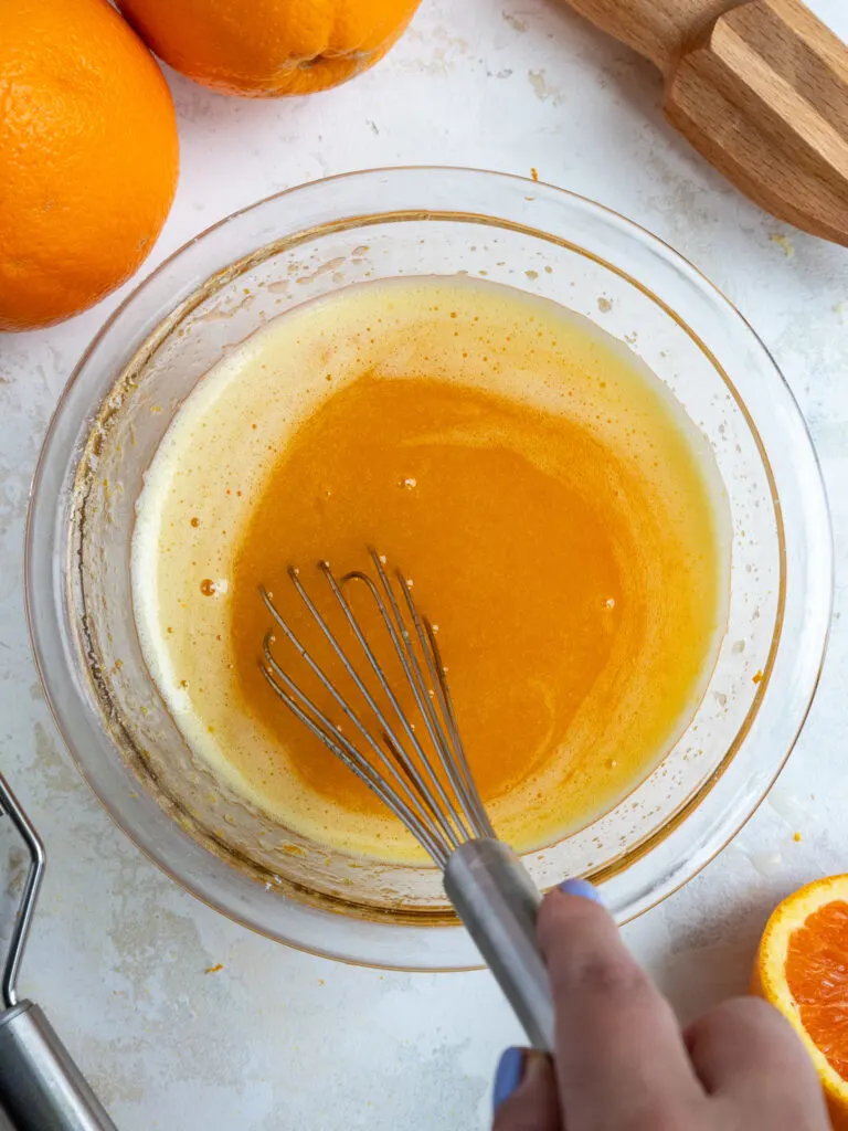 image of ingredients being mixed together to make orange curd in a glass bowl