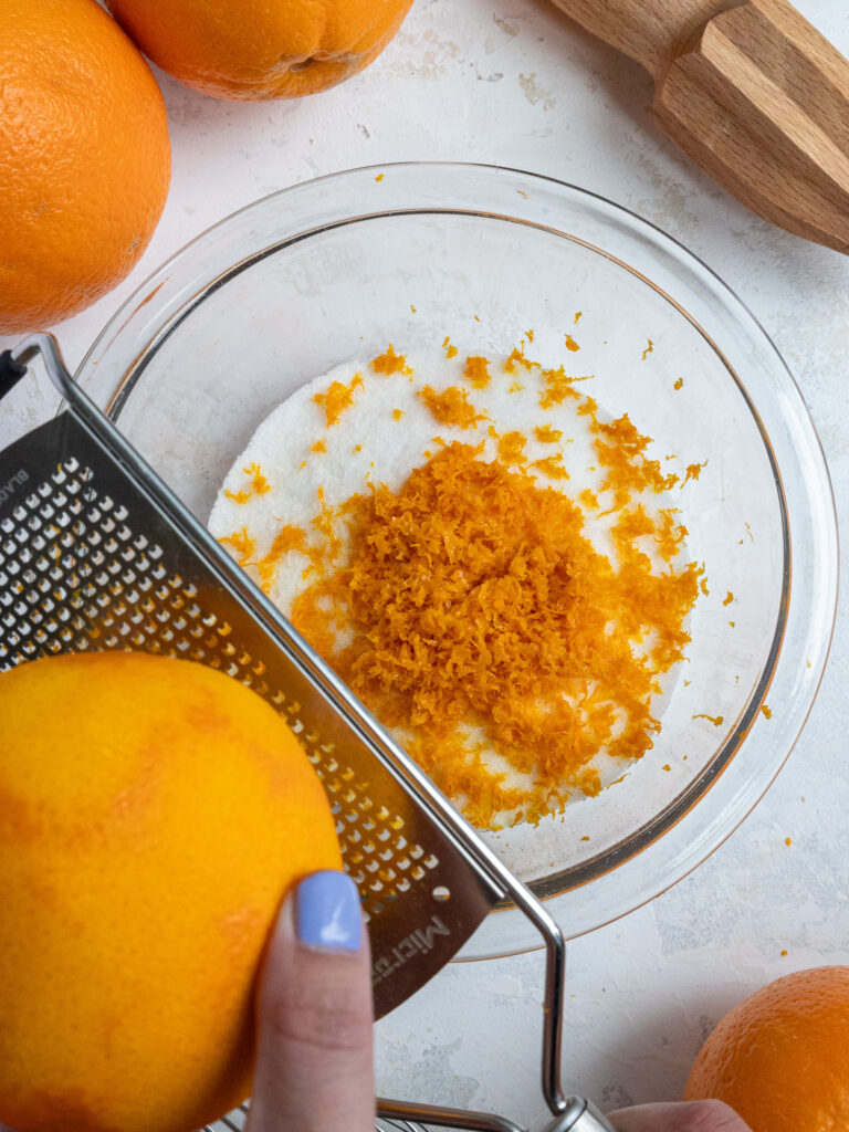 image of an orange being zested into a bowl of sugar