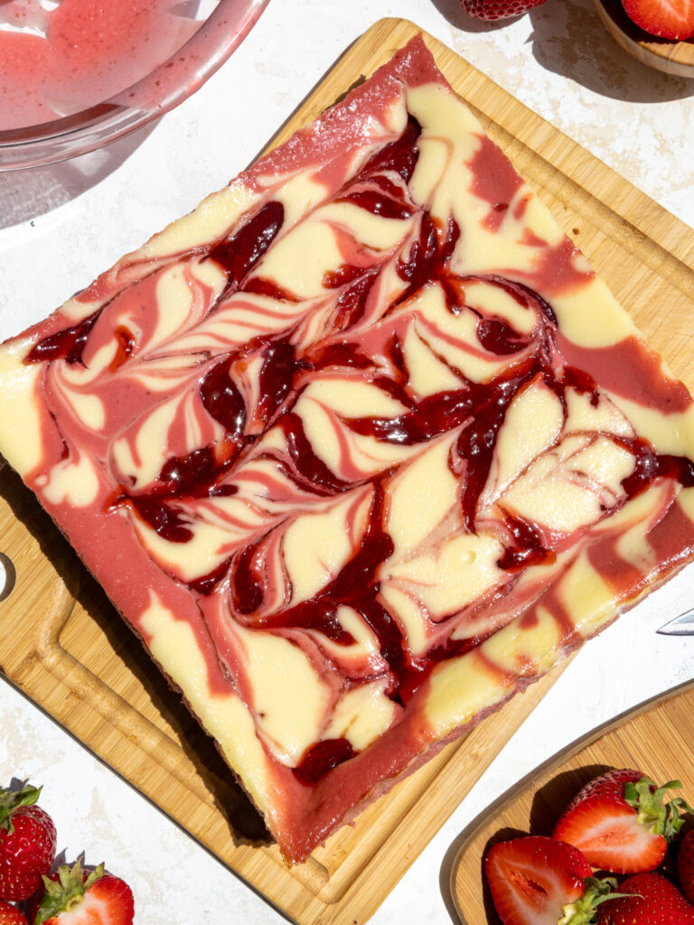 image of strawberry cheesecake bars that are baked and have a strawberry swirl