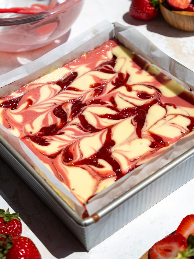 image of baked strawberry cheesecake bars cooling in a square metal pan