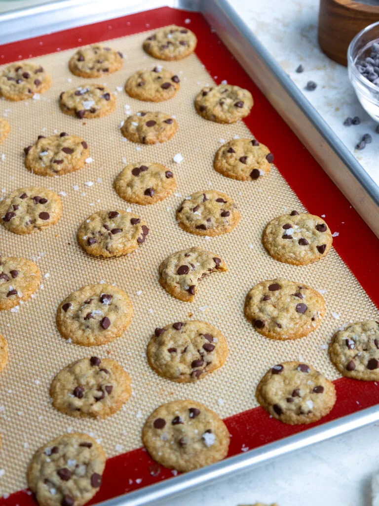 image of mini chocolate chip cookies that have been baked on a silicone mat and are cooling