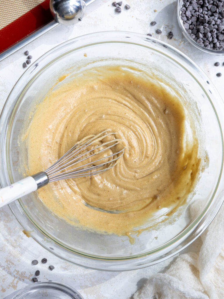 image of an egg and vanilla being whisked into a butter and sugar mixture to make mini chocolate chip cookies