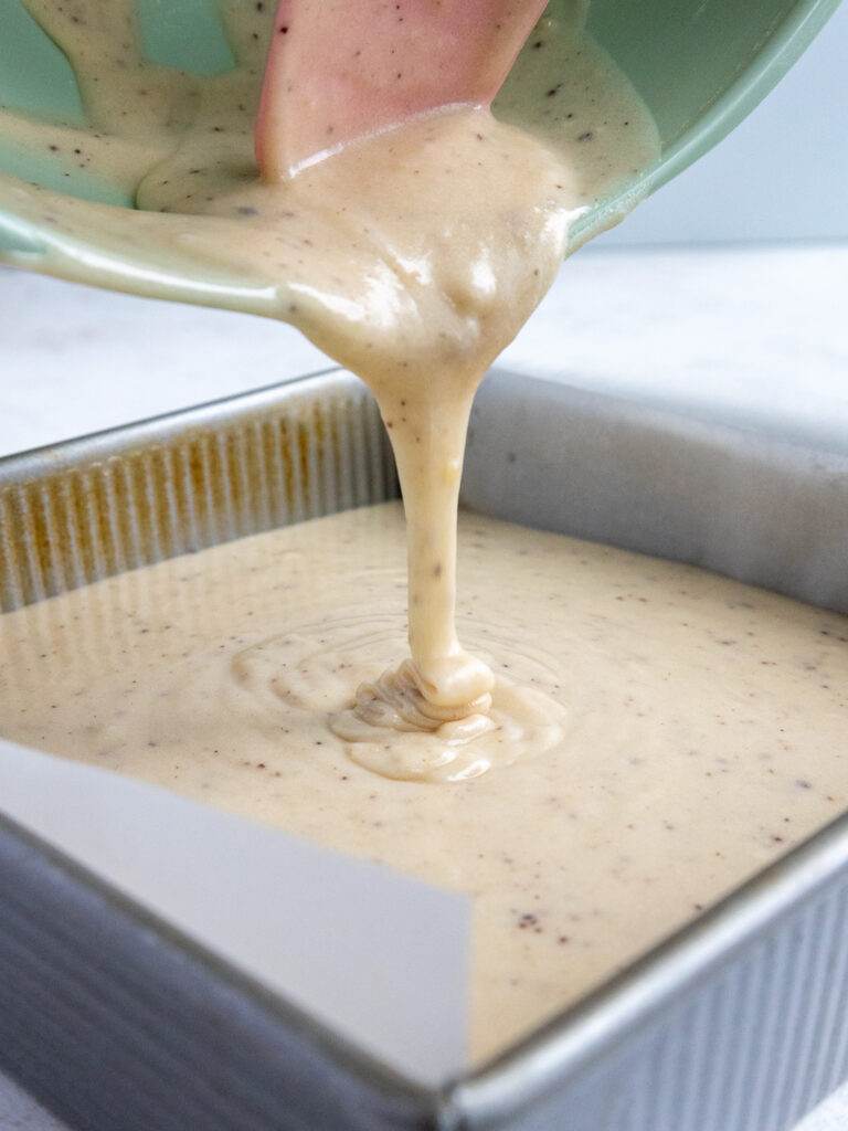 image of brown butter cake batter being poured into a square metal pan