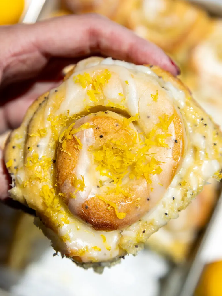 image of a lemon roll that's topped with lemon zest and is being held up in the sun